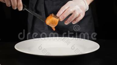 美味的菜肴。 餐厅食物烹饪。 厨师戴手套，把煎鳟鱼片放在白色盘子里。 慢动作。 高清高清